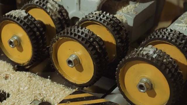 Spinning spiked wheels of plank refiner machine working on wood at carpenter production, close up