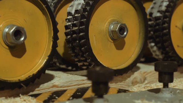 Spinning spiked wheels of board refiner machine working on wood at carpenter factory, close up