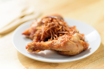 Fried chicken leg with fried onion on top ready for eating