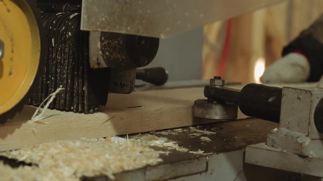 Rolling spiked wheels of plank refiner machine working on wood at lumber factory, close up