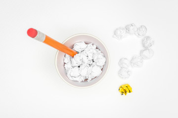 Crumpled paper balls on paper cup with pencil and question mark sign over white background