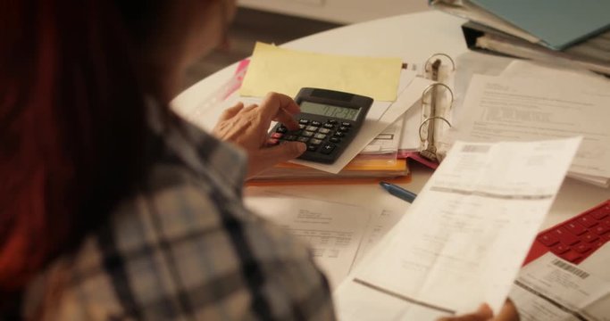 Elderly Woman Using Calculator For Taxes And Budget At Home