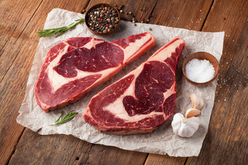 Two fresh raw marble meat, black Angus ribeye steak with spices on a old rustic table. Raw beef on a wooden background
