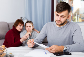 Upset guy with documents and dissatisfied family behind