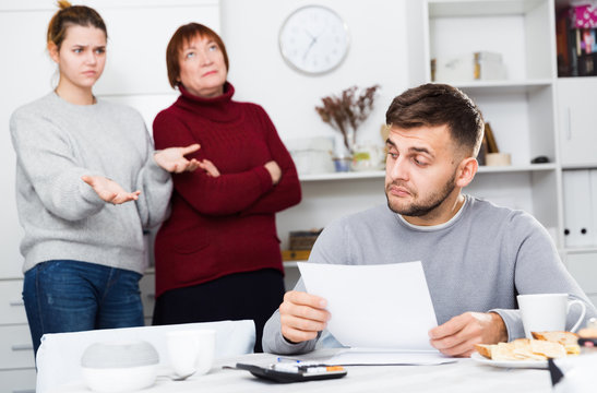 Frustrated man with papers on background with discontented family