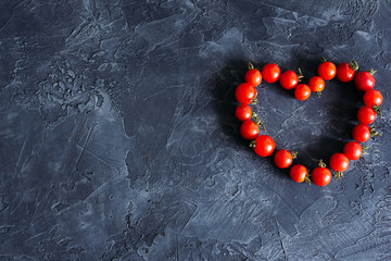 Tomatoes lie in the form of heart with copy space