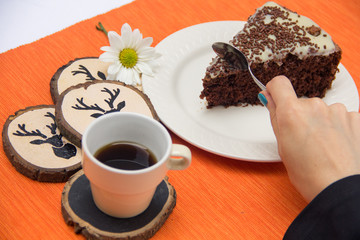 Chocolate cake slice with white chocoalte cream in plate with cup of coffee