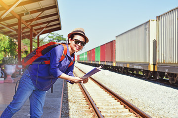 Fototapeta premium Young woman traveler with backpack and hat holding map with train background