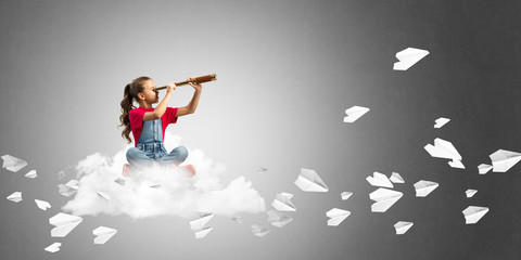 Concept of careless happy childhood with girl looking in spyglass