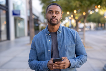 Young black man texting on cell phone walking