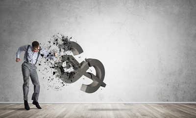 Determined banker man in empty concrete room breaking dollar figure