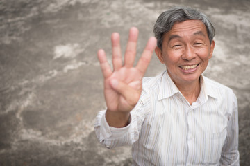Naklejka premium happy old man pointing up four fingers, smiling senior, positive retired pensioner portrait