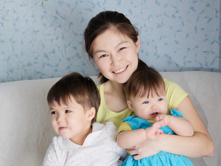 Happy smiling woman with two little girls, multinational family with Asian mother and Caucasian daughters