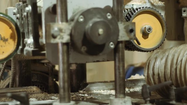 Rolling spiked wheels of bar refiner machine working on wood at sawmill production, close up