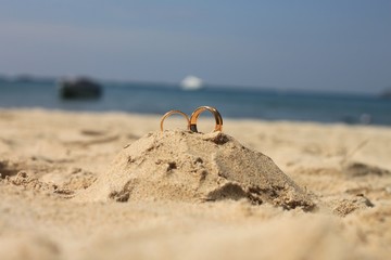 Obraz premium Wedding rings lie on sand castle