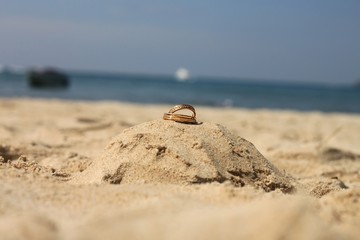 Wedding rings lie on sand castle at patong beach