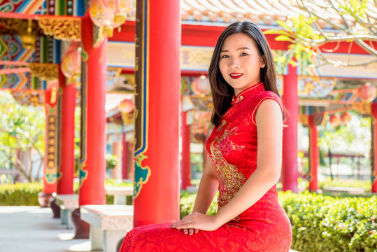 Smiling Asian woman in traditional red Chinese cheongsam qipao dress