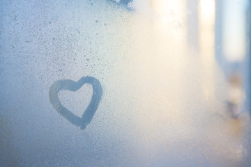 Figure of the heart on a frozen window in the city