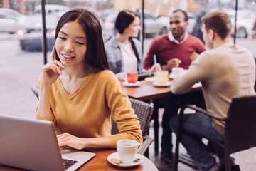 No distance. Joyful young nice woman relaxing at cafe while smiling and touching her face