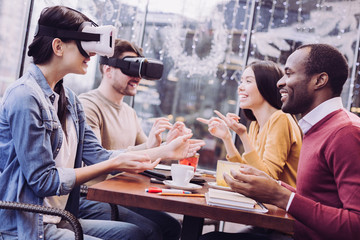 Virtual universe. Gay pleasant two friends trying VR headsets and resting at cafe while laughing