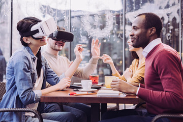 Virtual technology. Happy vigorous two friends using VR glasses while smiling and gesturing