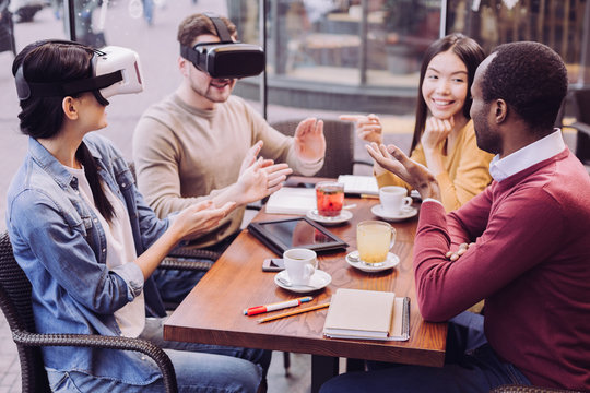 Sophisticated technology. Attractive appealing two friends using VR headsets while relaxing at cafe and communicating