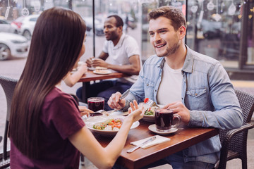 Plans for evening. Attractive energetic couple communicating and posing at cafe while handsome man smiling