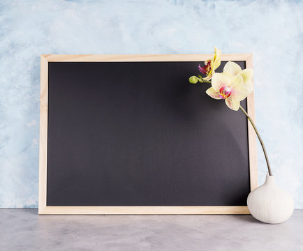 Back chalkboard mockup with yellow orchid in vase. Business, interior design, lettering concept. Text space