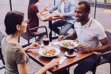 Healthy food. Top view of jolly glad attractive couple eating meal while looking at each other and chatting