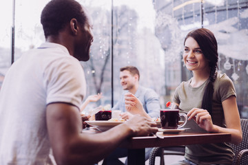 Pleasant lunch. Pleased satisfied irresistible woman holding fork while smiling and staring at man