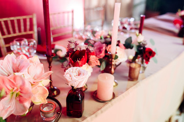 Decorated area in gold and burgundy colors with white candles and flowers