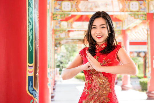 Asian woman in traditional red dress making salute
