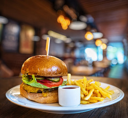 Fresh tasty burger and french fries on wooden table.