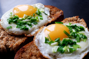 two fried eggs on bread filling spring green onion close up
