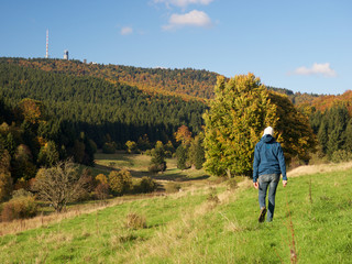 Wanderer läuft  im Herbst im Mittelgebirge mit Inselberg