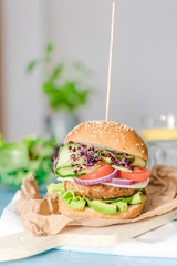 Tasty vegan burger with fresh vegetables on dark rustic wooden table, selective focus. Healthy fast...