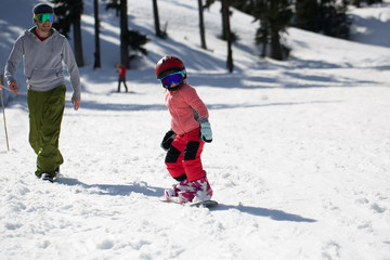 Fototapeta na wymiar At Sunny Cold Winder Day at Mountain Ski Resort Mount Hood Meadows Oregon Father Teaching Little Daughter Snowboarding 
