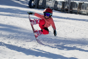 Fototapeta na wymiar Little Cute Girl Snowboarding making a tricks at ski resort in sunny winter day. Caucasus Mountains. Mount Hood Meadows Oregon 