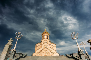 Fototapeta na wymiar The Holy Trinity Cathedral or Tsminda Sameba Church, Tbilisi, Georgia. Georgian Orthodox church with dramatic rainy sky with clouds on the background.