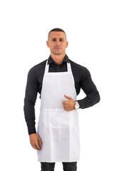 Young chef or waiter posing, welcoming guests with a smile, wearing black apron and white shirt isolated on white background
