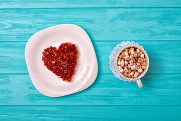 Cheese pancake in the form of a heart and a cup of coffee with marshmallows. A sweet surprise for a loved one.