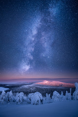 Milky way and stars glowing on the sky above winter landscape