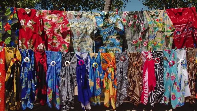 Colourful floral T-shirts and bright beach scarfs hanging for sale on Mayreau island, Caribbean region
