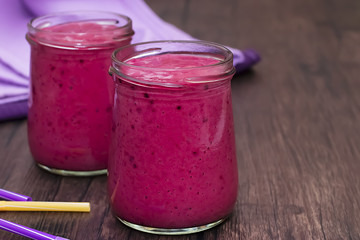 Berry smoothies and purple napkin in glass bowls.