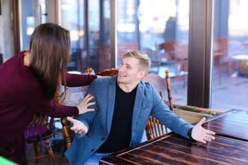 Writer with smartwatch on hand waiting business partner in cafe and suddenly meet former classmate, imposing guy wearing blue jacket and black T-shirt checking time looking out window. Asian