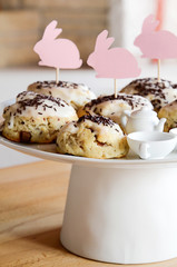 Chocolate scones on cake stand with cut out paper bunnies served for teatime on easter