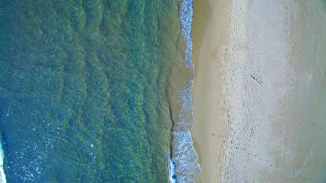 Aerial view waves break on white sand beach