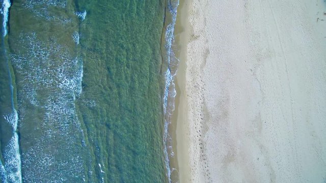Aerial view waves break on white sand beach