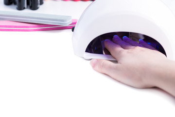 Woman put hand in led lamp dryer on white table