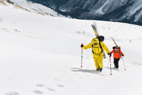two ski freerider climbs the slope into deep snow powder with the equipment on the back fixed on the backpack.